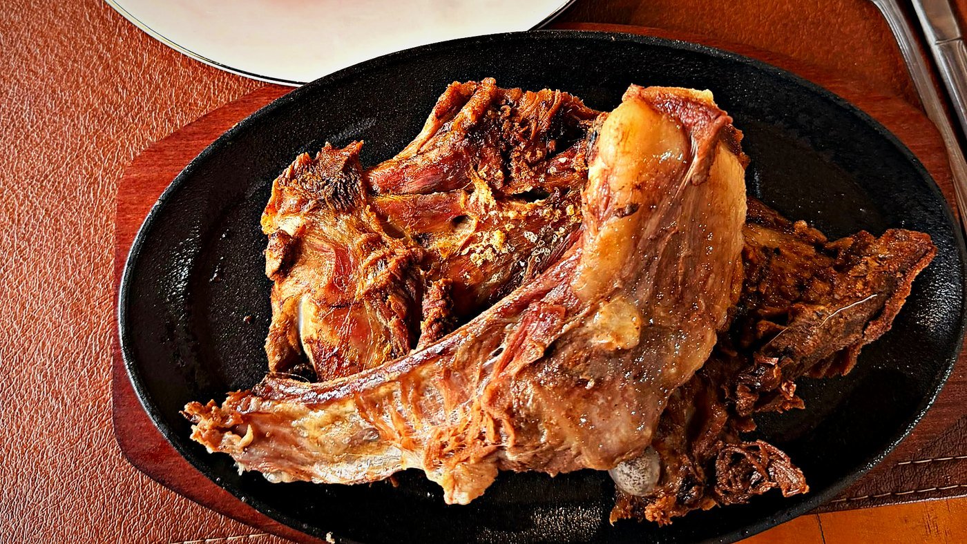 Asado de chivo dorado en plancha de hierro