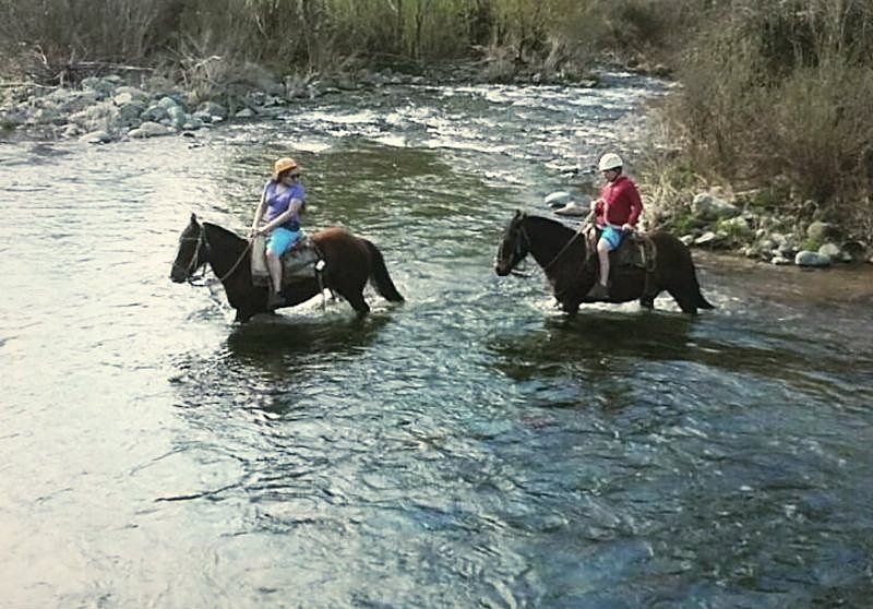 Dos jinetes cruzando el río a caballo