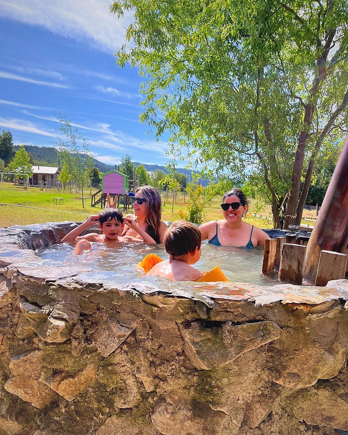Familia en la tinaja de piedra con los juegos infantiles de fondo
