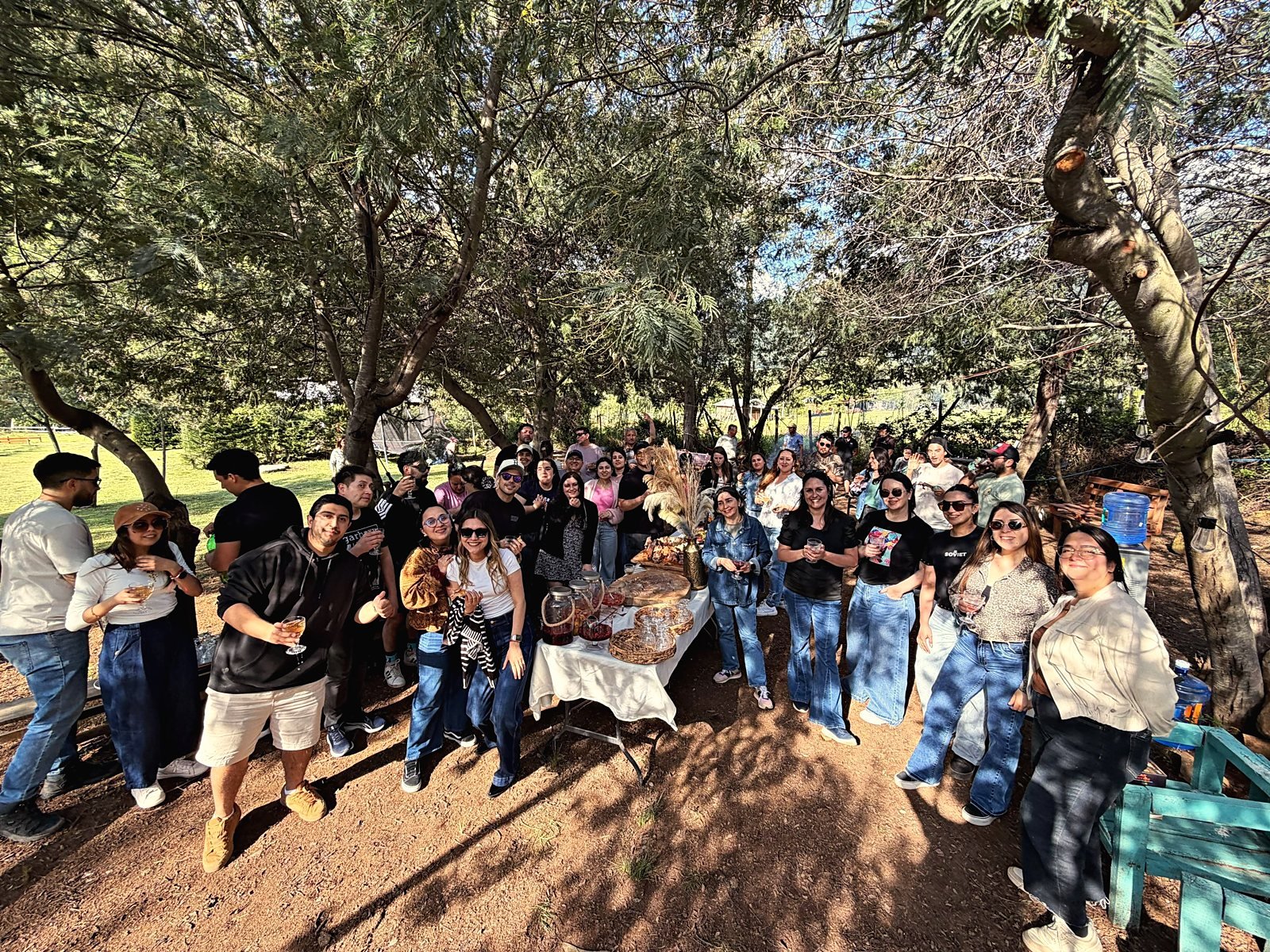 Grupo brindando con sangrías bajo los árboles junto a la mesa del tardeo