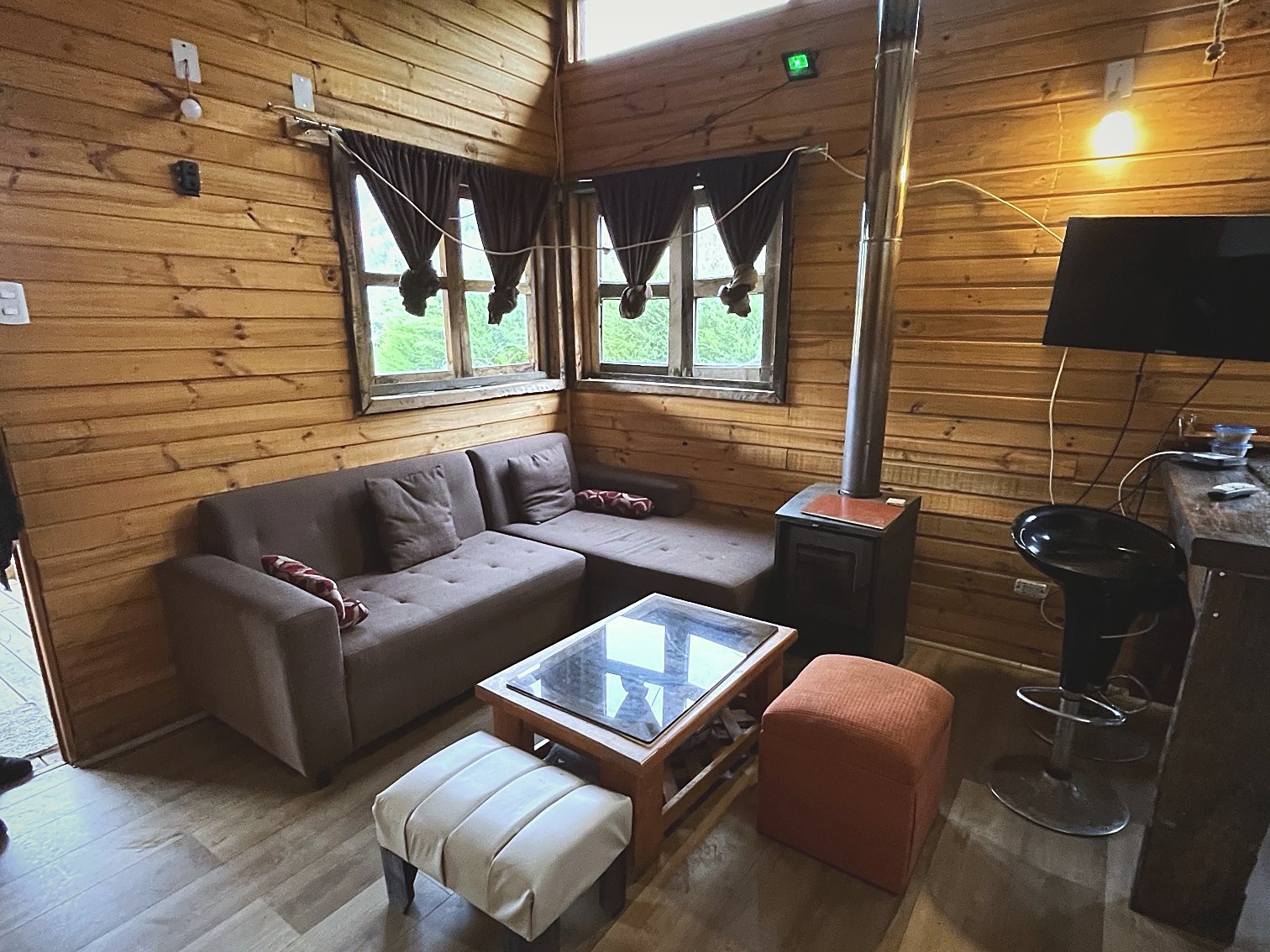 Living con sofá en L y estufa a leña de la cabaña Araucaria
