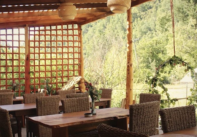 Terraza del restaurante con mesas de madera bajo el quincho
